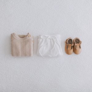 Folded baby jumper, pants and shoes in a row