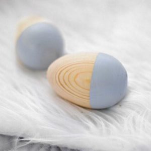 Natural timber and grey egg shakers on white fluffy rug
