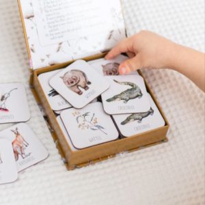 Open box of Snap & Go fish on white bed with child hand picking a card up